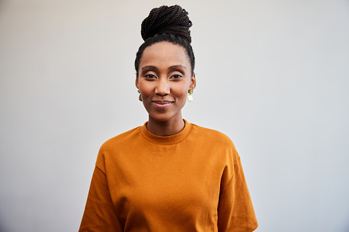 Portrait of a young businesswoman smiling while standing in front of a white wall in an office